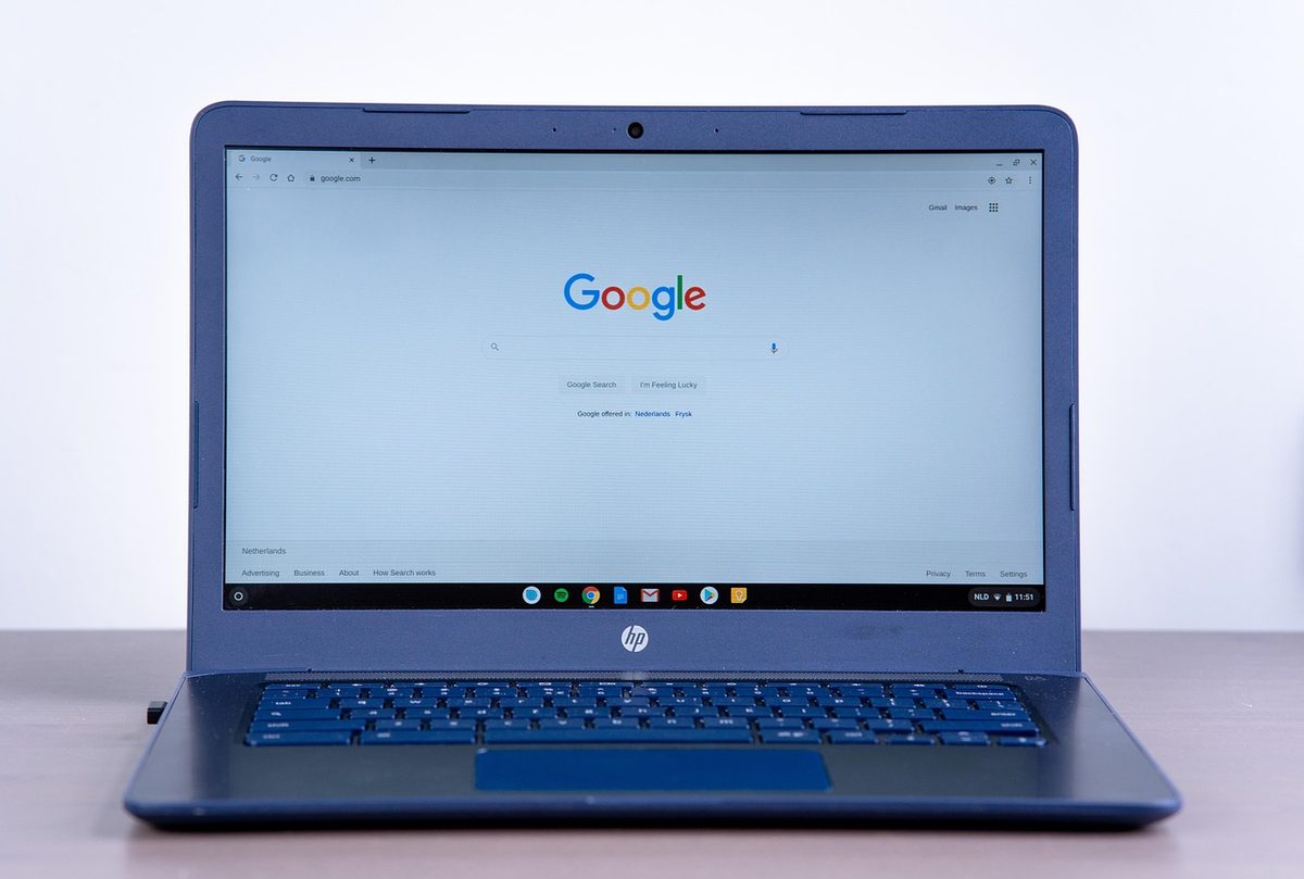 A blue HP laptop on a desk showing the Google search homepage