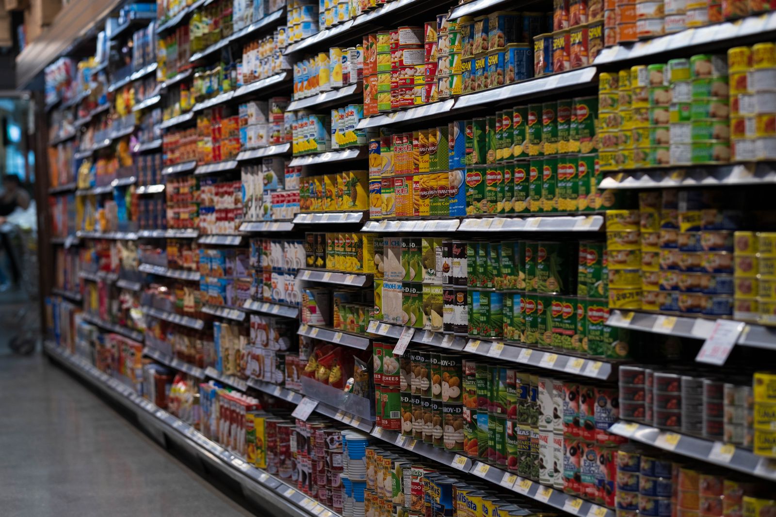 Un pasillo de supermercado con estanterías llenas de conservas que se extienden a lo lejos