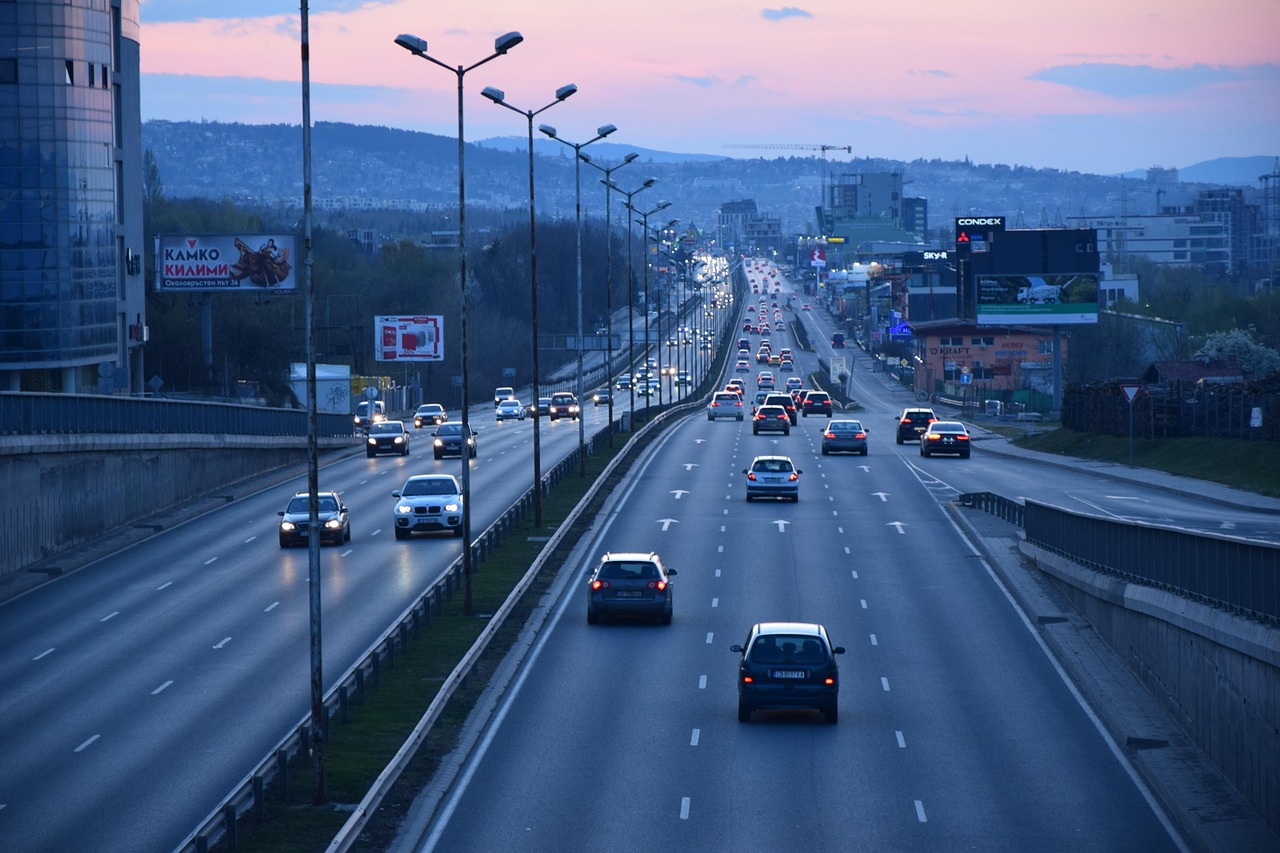 Transito ao fim do dia numa autoestrada urbana com varias faixas. Os leitores automaticos de matriculas fotografam cada carro que passa e registam a matricula com hora e local.